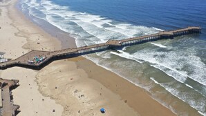 Un pontó que s'endinsxa a l'oceà, amb una platja d'un costat i una passarel·la de l'altre.
