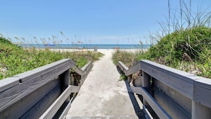 A concrete pathway leading to a beach with wooden railings on both sides. - Oceans of Amelia Condos (Fernandina Beach)