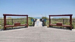 A wooden boardwalk leading to a beach with railings and benches. - Oceans of Amelia Condos (Fernandina Beach)