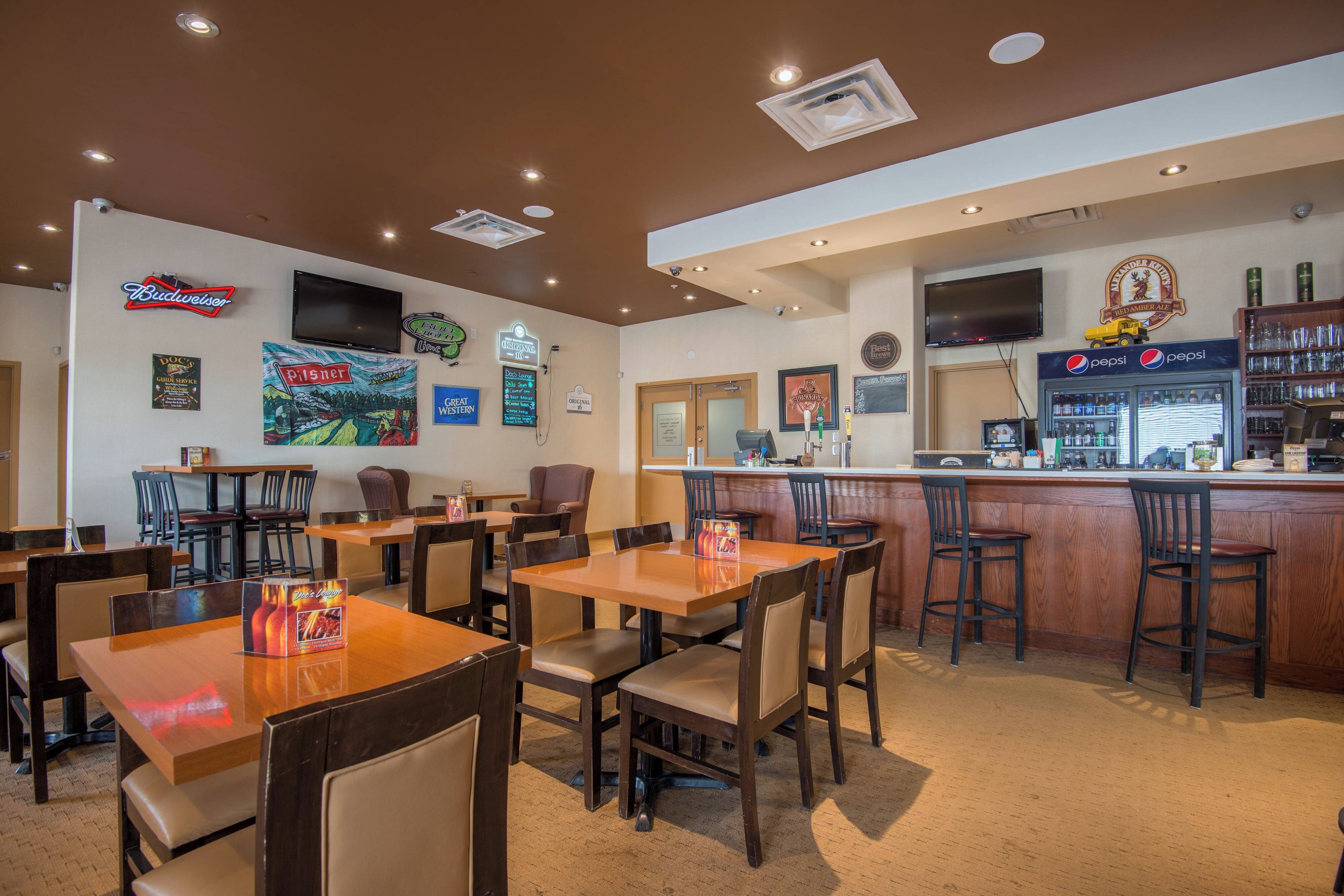 Un restaurante con varias mesas y sillas, una zona de bar y diferentes decoraciones en las paredes, incluyendo letreros y un televisor.