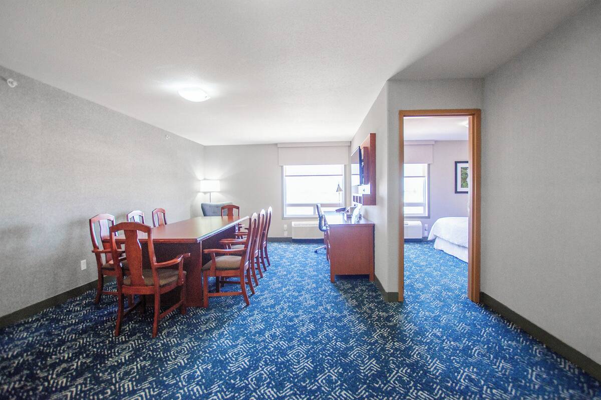 A hotel room with a dining area, a desk, and a bed.