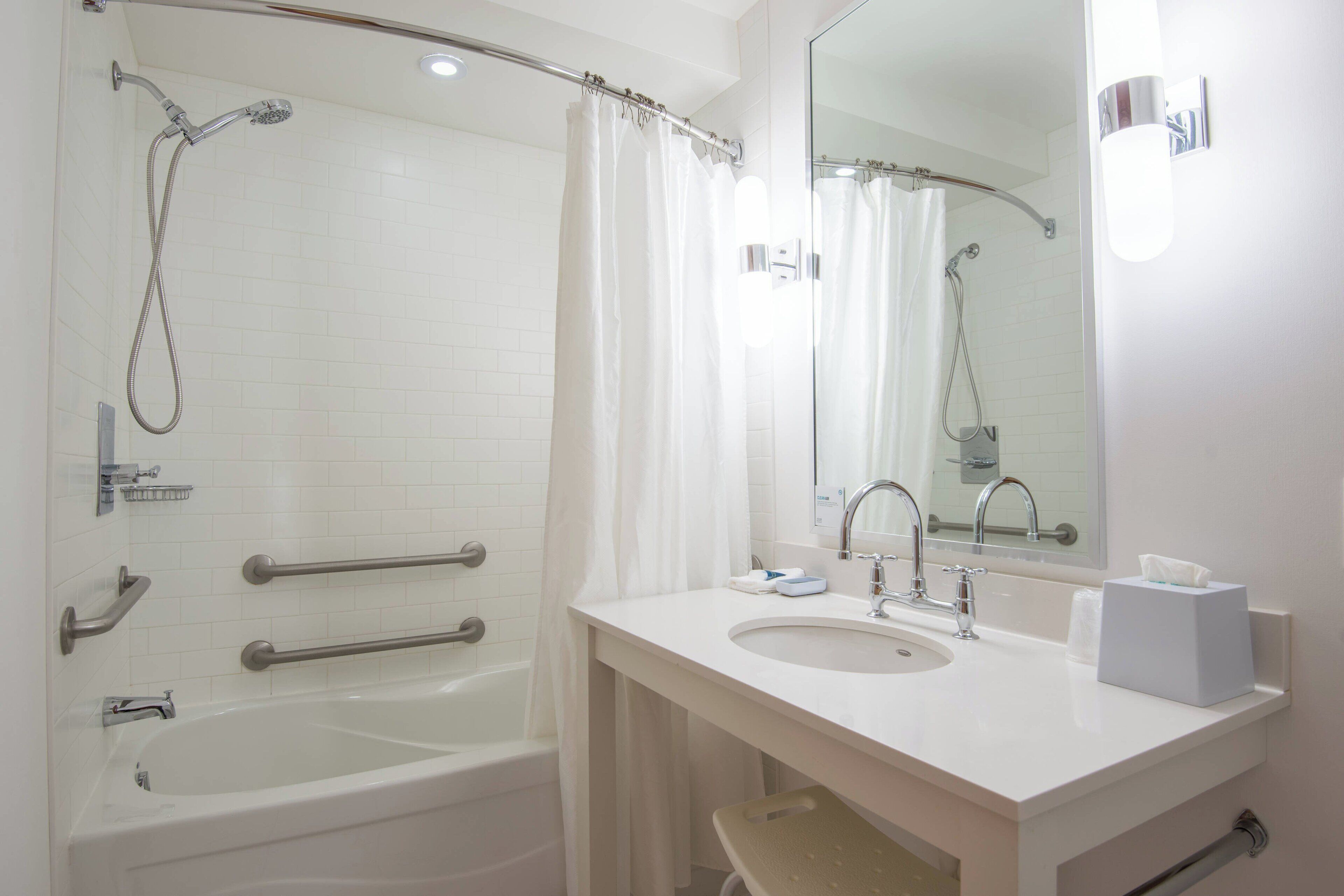 A bathroom with a bathtub, a sink, a mirror, and a shower.
