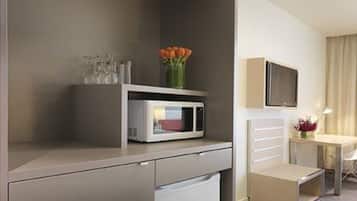 A compact kitchenette with a microwave, a small refrigerator, and a glass cabinet.