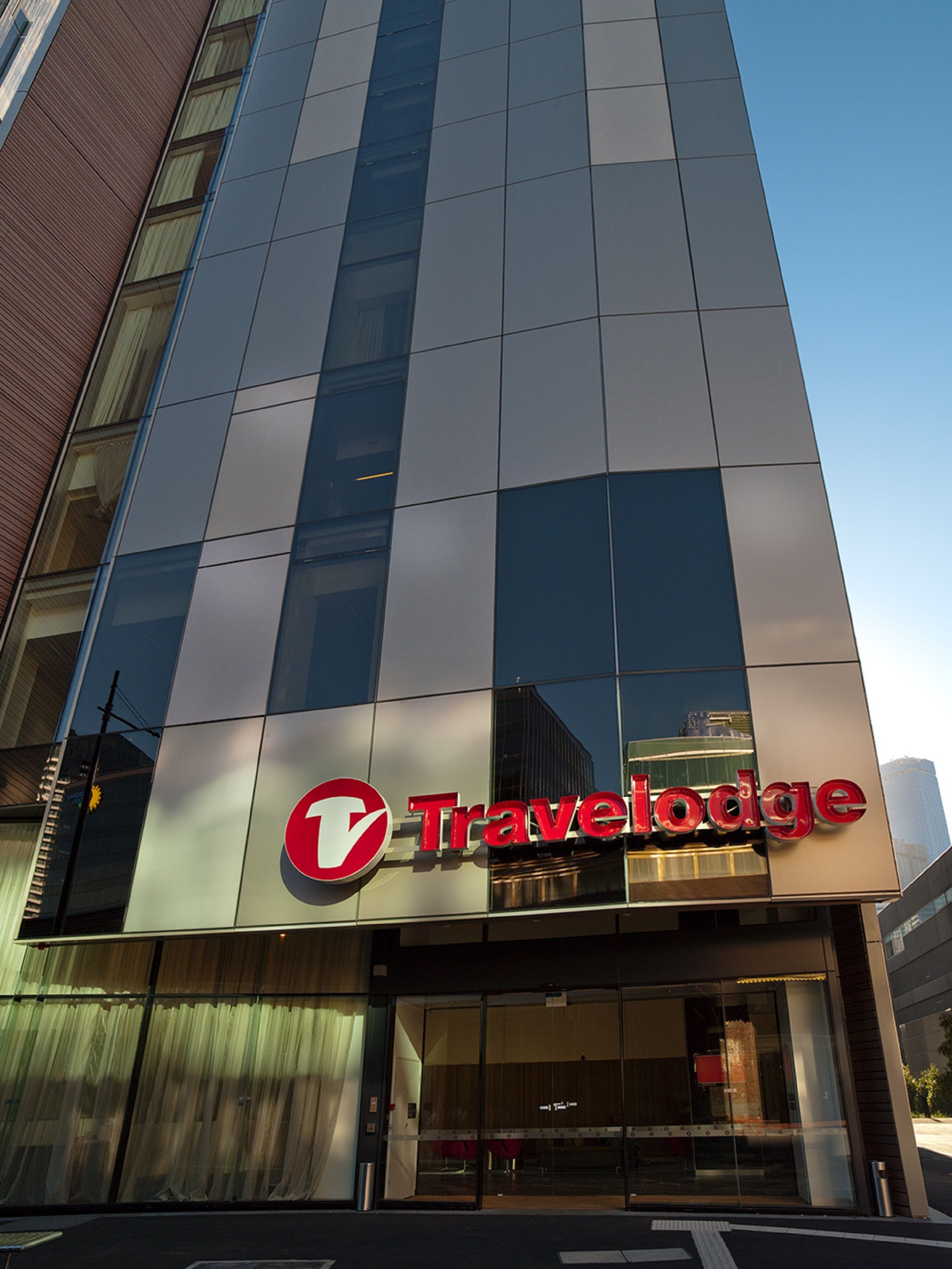 A modern building with a large glass facade and a prominent Travelodge sign.