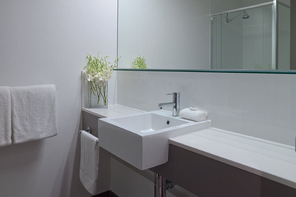 Een moderne badkamer met een grote spiegel, twee wasbakken en een douche.
