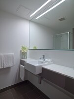 Un baño moderno con un espejo grande, dos lavamanos y una ducha.