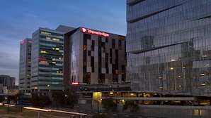 A modern hotel with a prominent Travelodge sign, multiple floors, and a glass facade reflecting the cityscape.