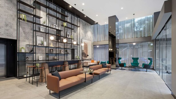 A modern interior with a sectional sofa, bar stools, and a large window with sheer curtains.