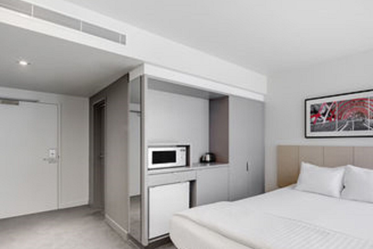 Een moderne hotelkamer met een bed, een magnetron en een kleine kitchenette.