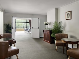 Une chambre d’hôtel dotée d’une grande fenêtre, d’un coin repas avec une table et des chaises, d’un meuble en bois et d’une plante en pot.