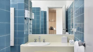 Un baño moderno con azulejos azules, un lavamanos, un espejo y un suelo con diseño.