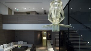 Un intérieur moderne avec un canapé d’angle, une table basse et un luminaire suspendu original.