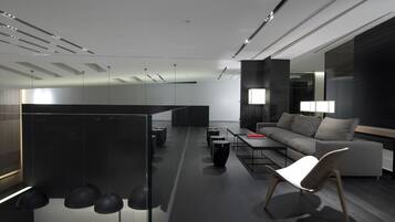 A modern office space with a sofa, a coffee table, and a desk area.
