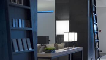 Ein modernes, minimalistisches Hotelzimmer mit einem großen Bett, einem Nachttisch und einer integrierten Bücherwand.