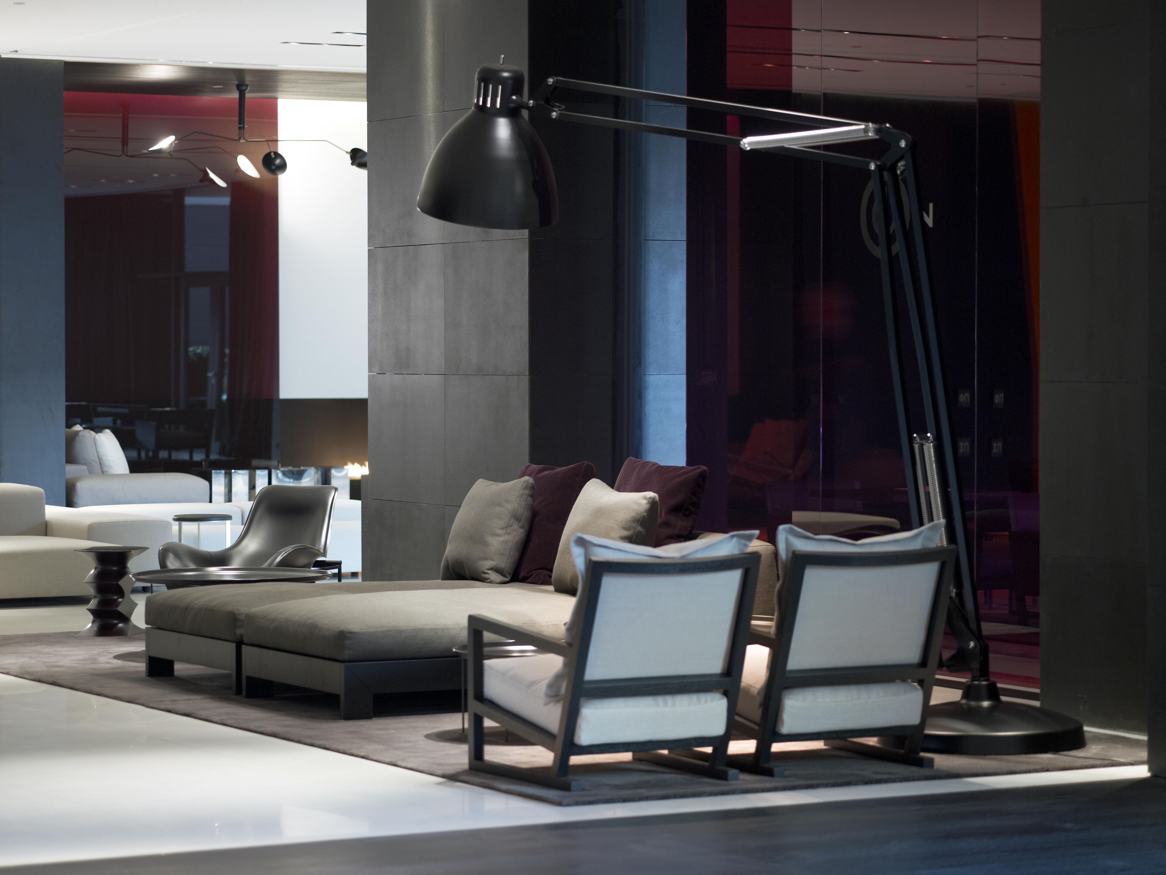 Una sala de estar moderna con un sofá, dos sillones, una lámpara de pie y un ventanal grande.