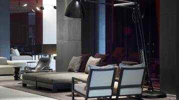 A modern living room with a sofa, two armchairs, a floor lamp, and a large window.