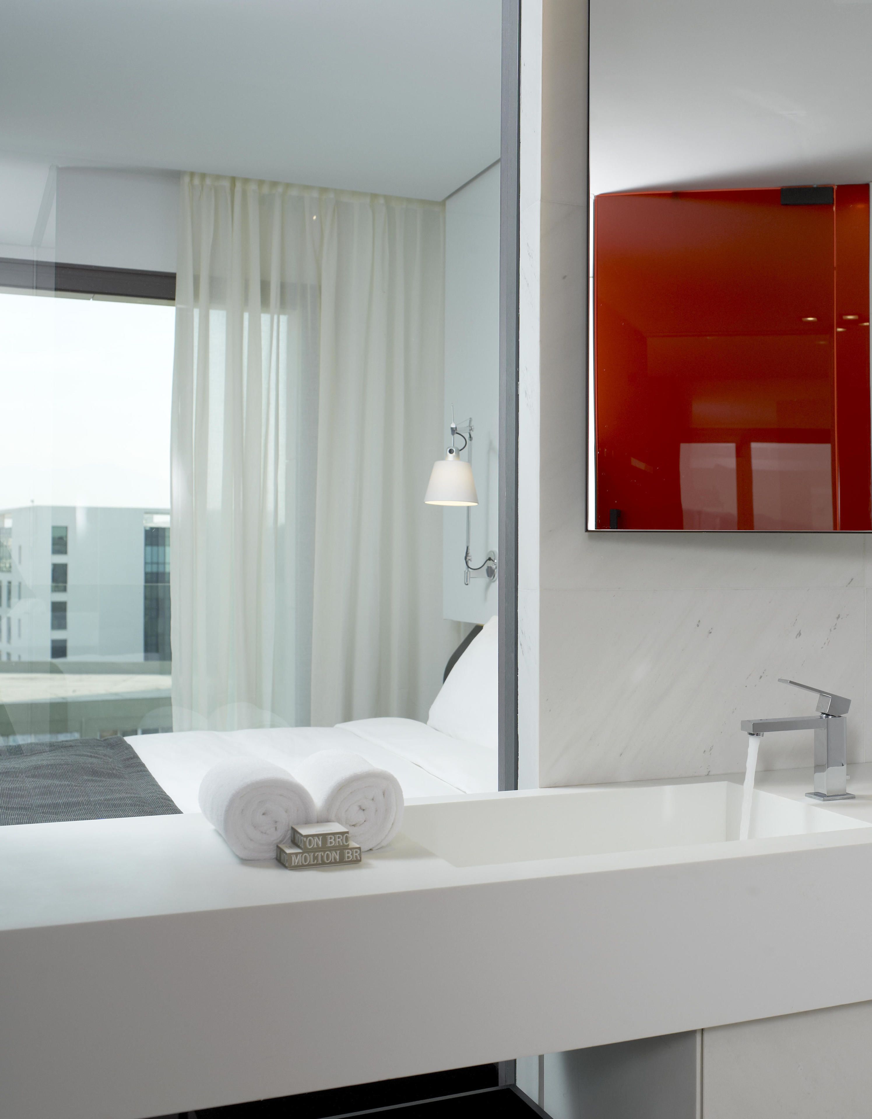 A modern bathroom with a white sink, a towel, and a mirror.