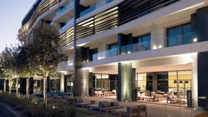 Un hôtel moderne doté d’une piscine, d’un espace extérieur aménagé et d’une entrée bien éclairée.
