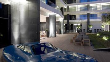 A modern building with a blue car parked in front.
