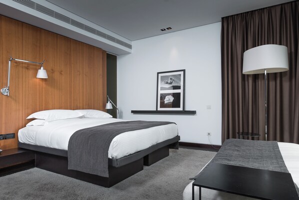 A modern hotel room with a bed, bedside table, lamp, and a desk with a chair. - The Met Hotel, a member of Design Hotels (Thessaloniki)