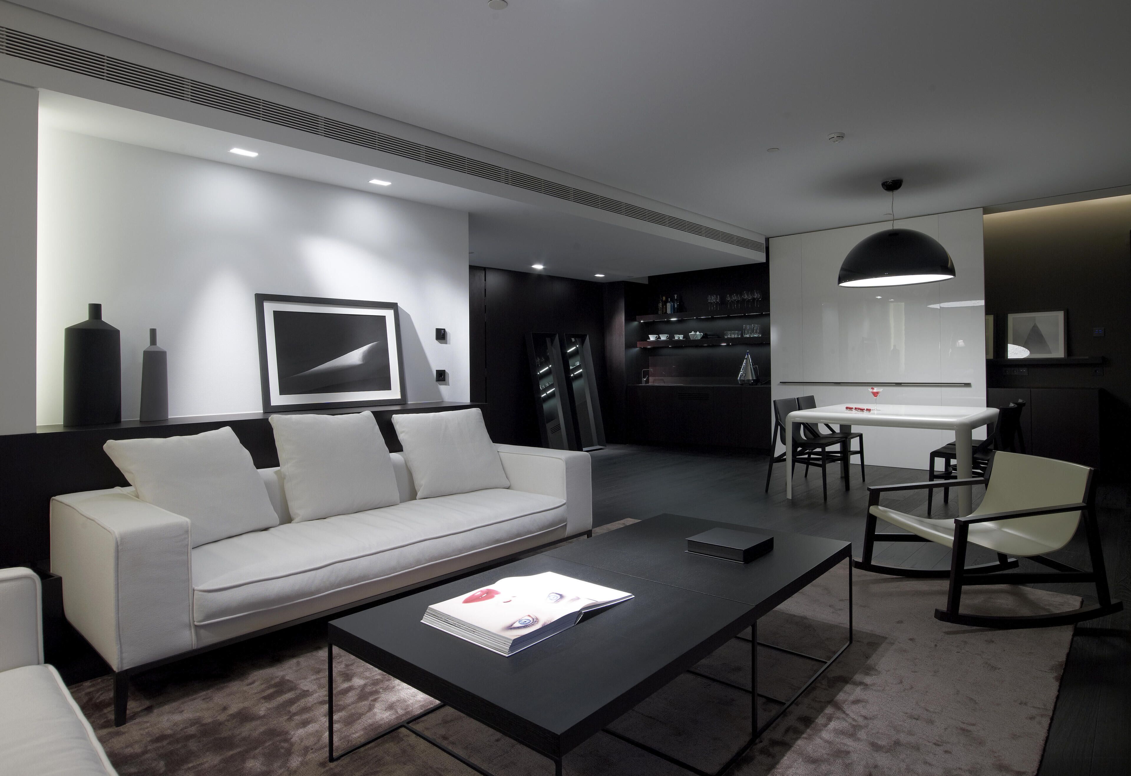 Una sala de estar moderna con un sofá blanco, una mesa de centro y un comedor con mesa y sillas.