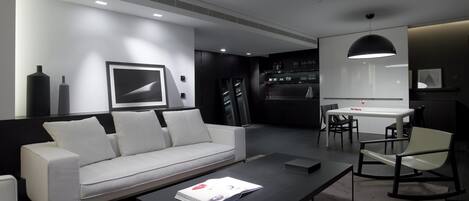 Una sala de estar moderna con un sofá blanco, una mesa de centro y un comedor con mesa y sillas.