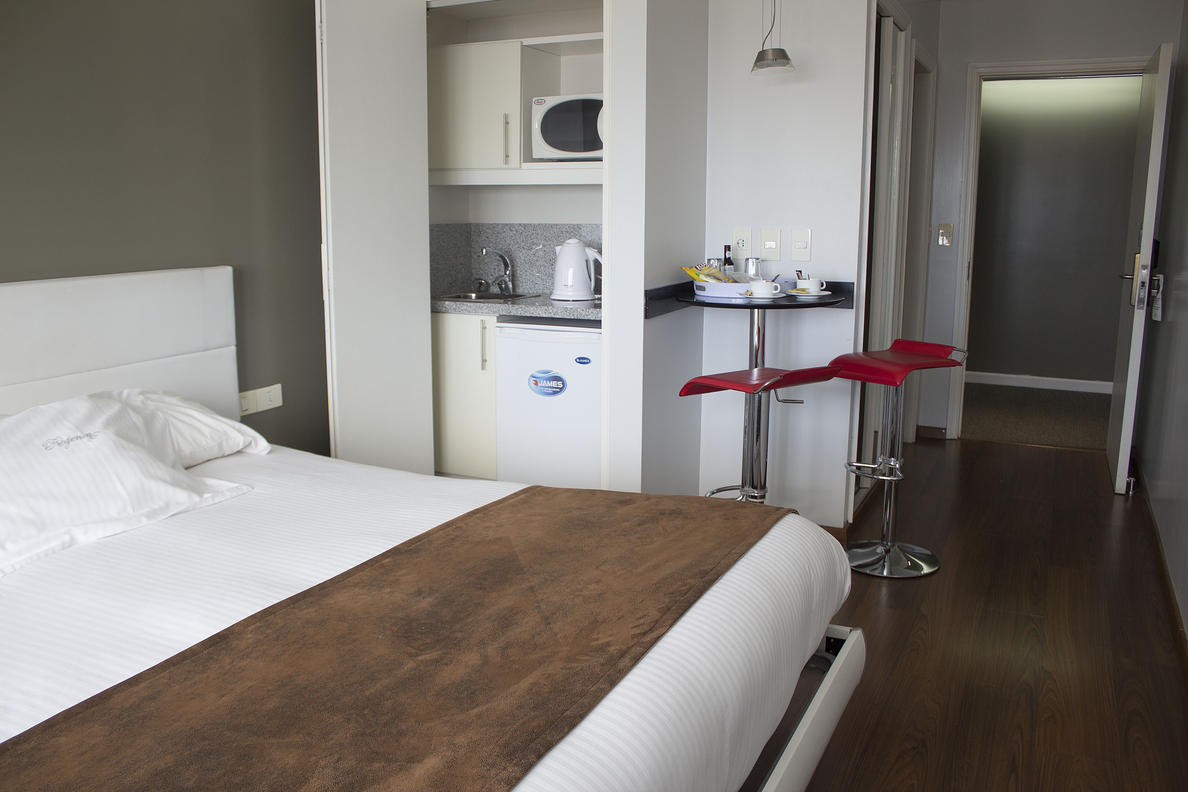 Habitación de hotel con cama, kitchenette y una silla roja.