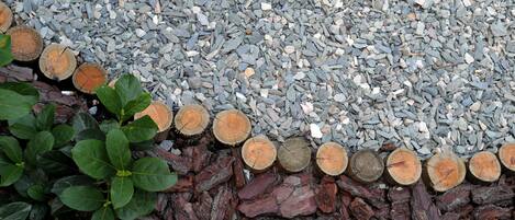 A gravel path with wooden logs and green foliage.