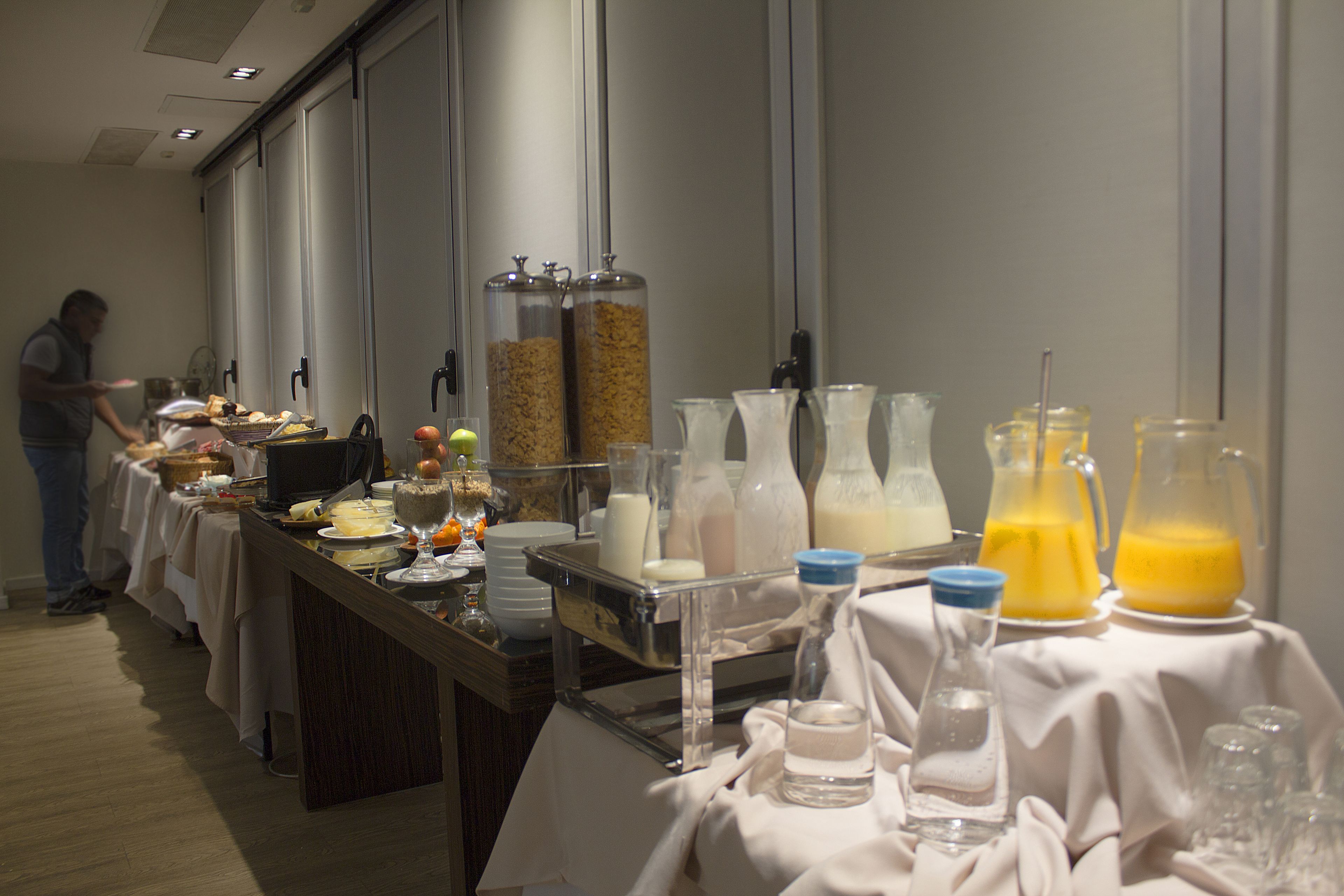 Montaje de bufé con diversas opciones de comida y bebida, que incluye una estación de bebidas con dispensadores de leche y jugo.