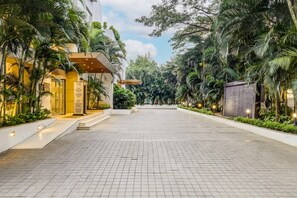 A spacious, well-lit entrance area with a tiled floor, surrounded by lush greenery and palm trees. - Lemon Tree Hotel, Electronics City - Bengaluru (Bengaluru)