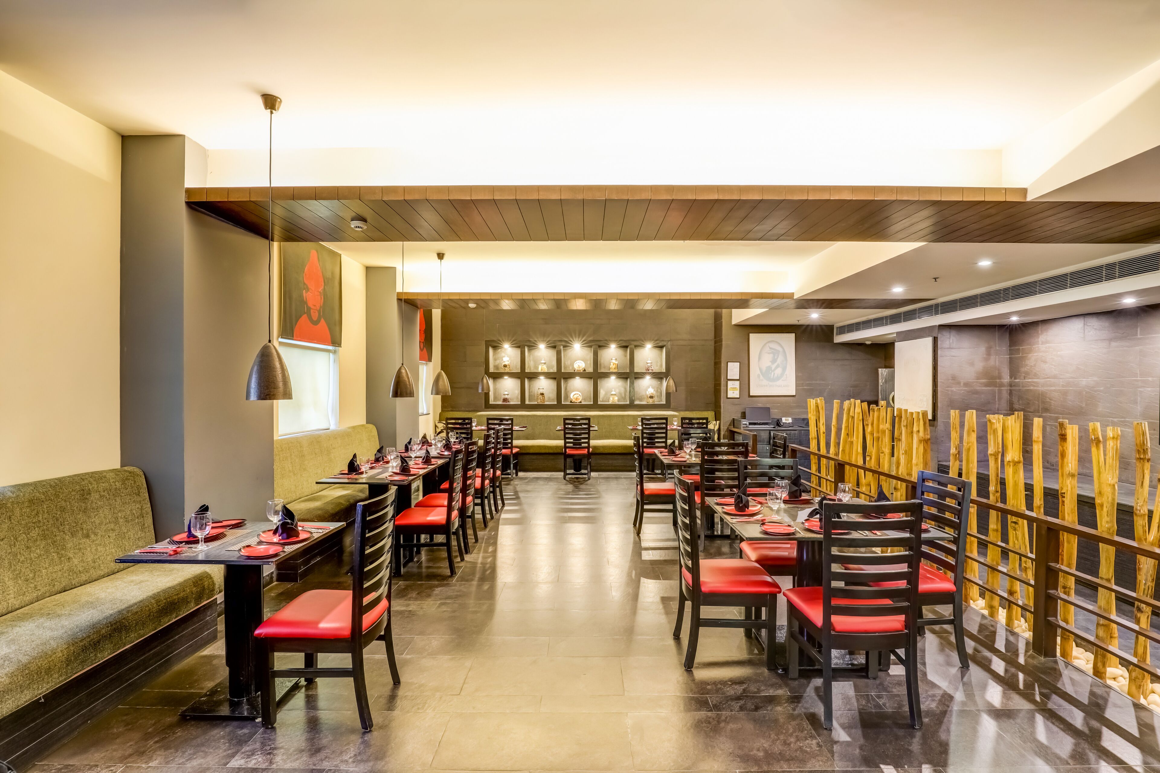 Un restaurante con mesas largas y sillas rojas, techo de madera y una pared con cuadros enmarcados.