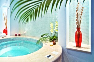 Un área de spa con un jacuzzi, una ventana y un jarrón rojo, además de una pared con azulejos.