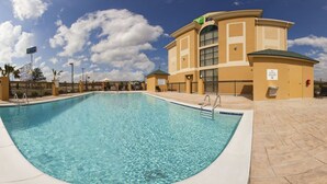 A swimming pool with a clear blue water, surrounded by a beige building with a green roof and a sign indicating no diving allowed. - Holiday Inn Express Hotel & Suites CORDELE NORTH by IHG (Cordele)