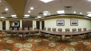 A conference room with a long table and chairs, carpeted floor, and framed pictures on the wall. - Holiday Inn Express Hotel & Suites CORDELE NORTH by IHG (Cordele)