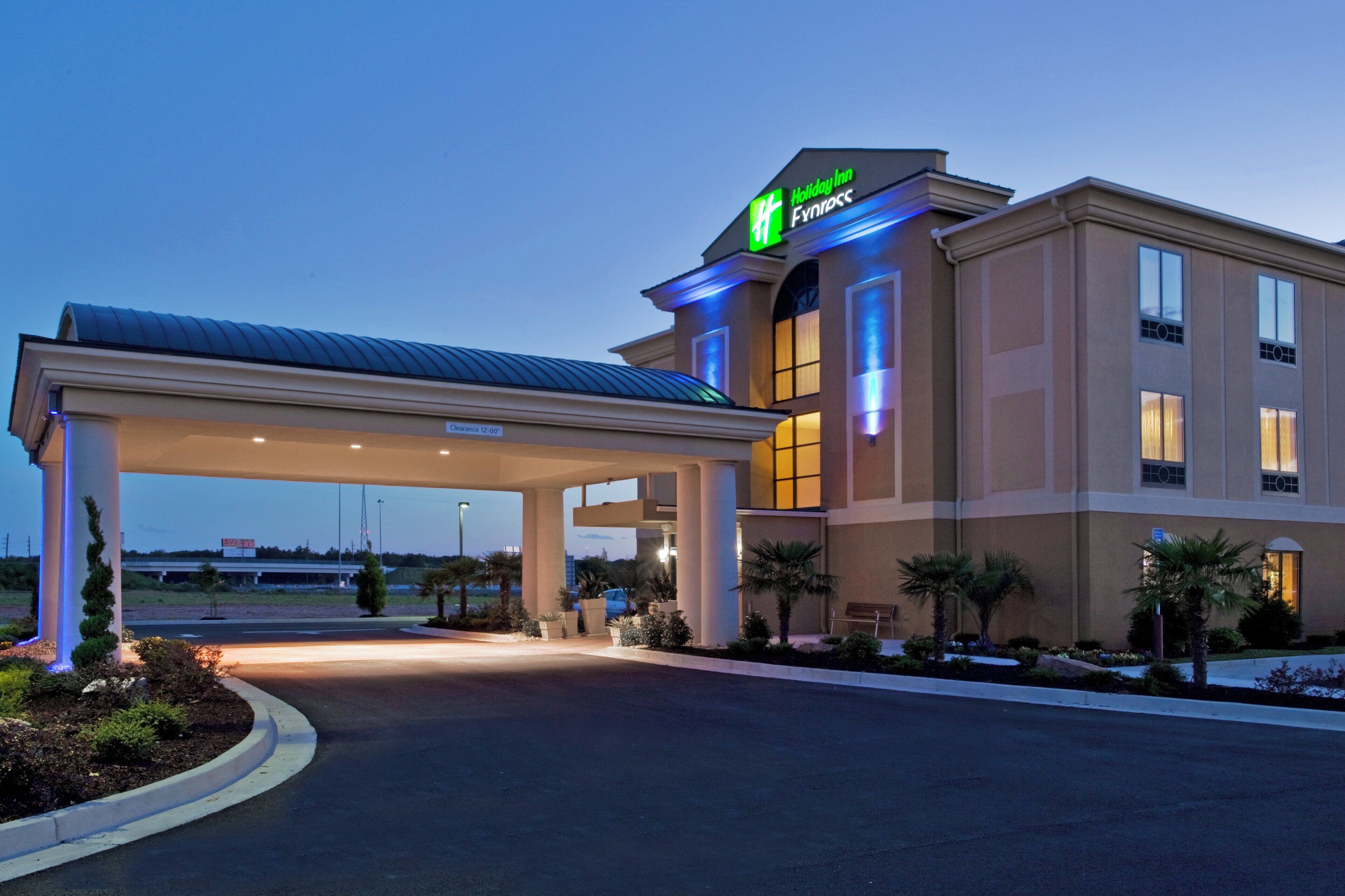 A Holiday Inn Fynkros building with a covered parking area and a clear sky.