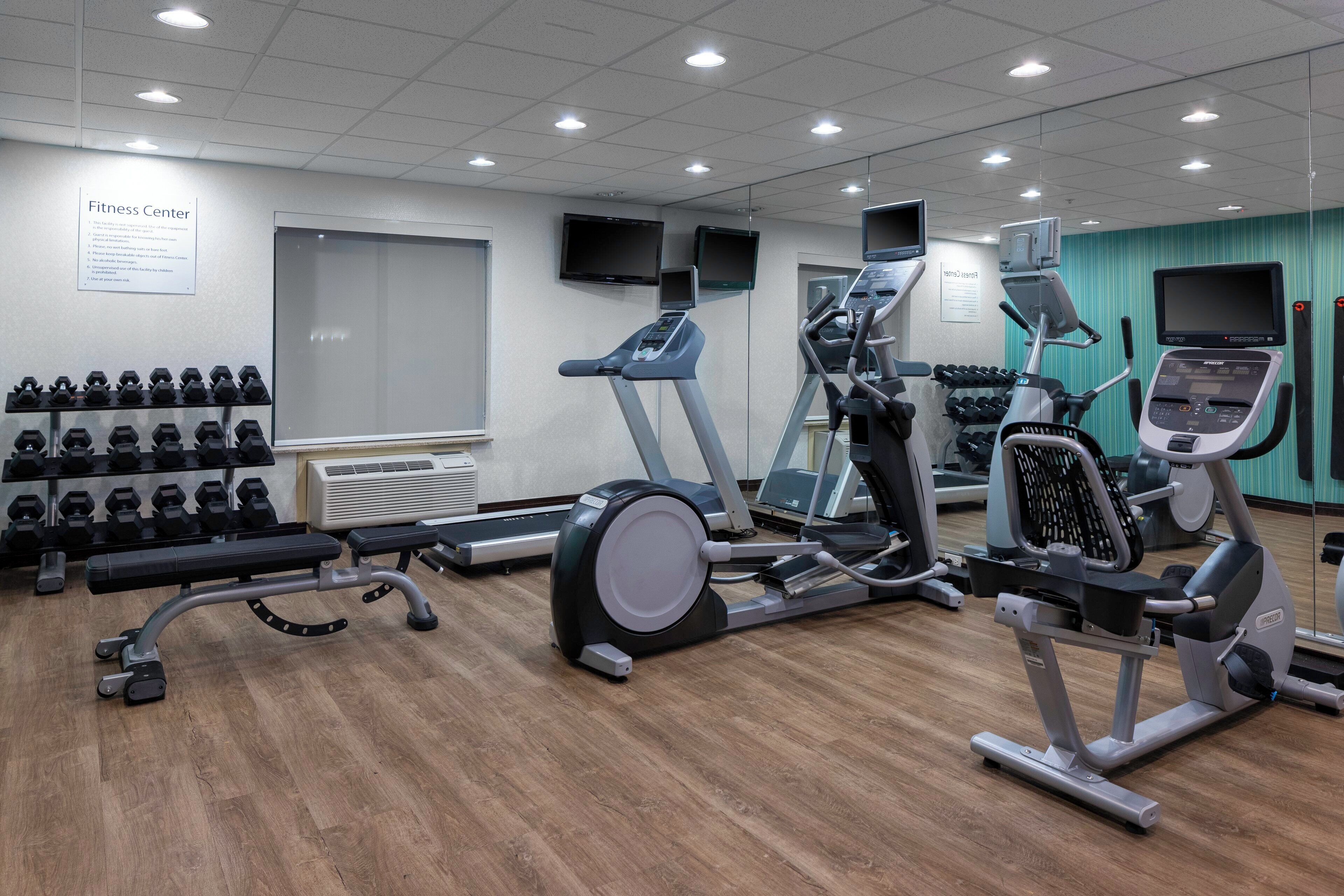 Un centre de remise en forme équipé de tapis de course, de vélos elliptiques et de poids libres.