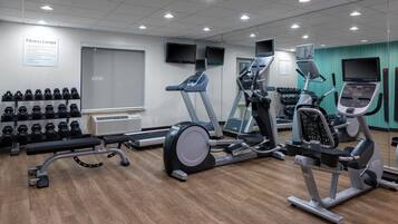 Un centre de remise en forme équipé de tapis de course, de vélos elliptiques et de poids libres.