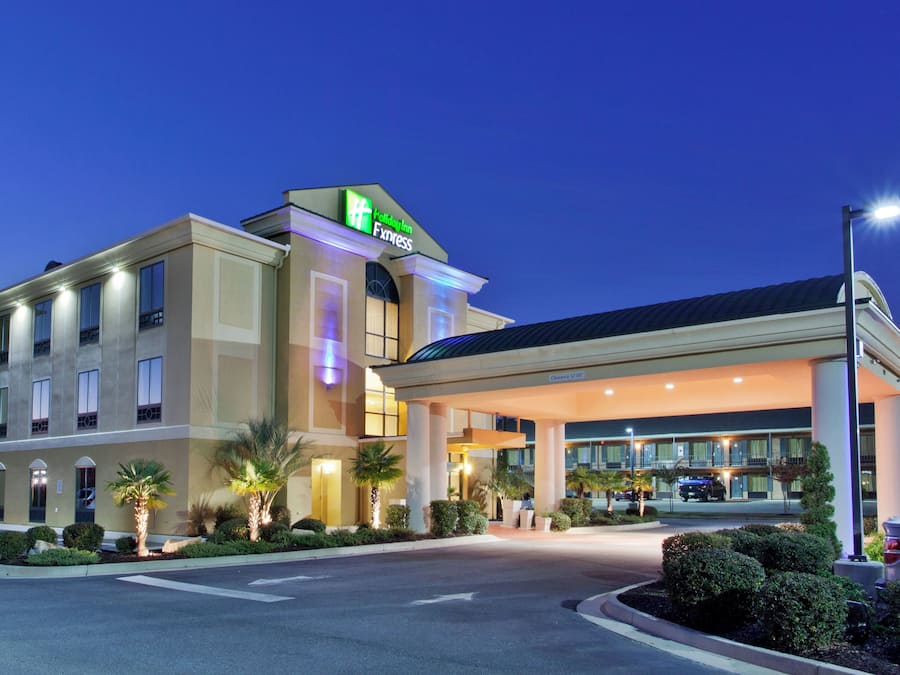 A Holiday Inn Express hotel with a covered entrance, palm trees, and a clear sky.