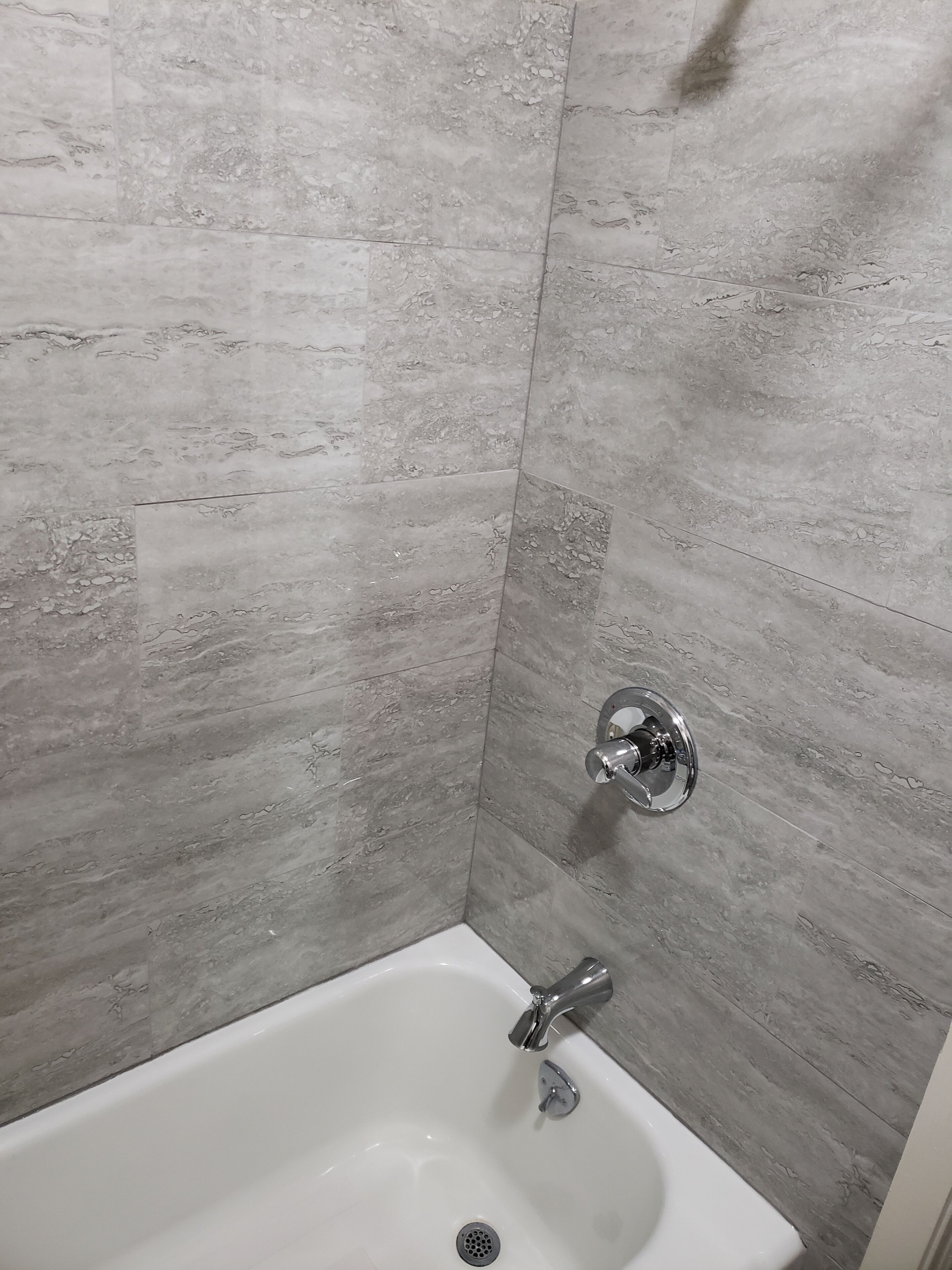 A bathroom with a white sink and chrome fixtures, set against a grey marble wall.