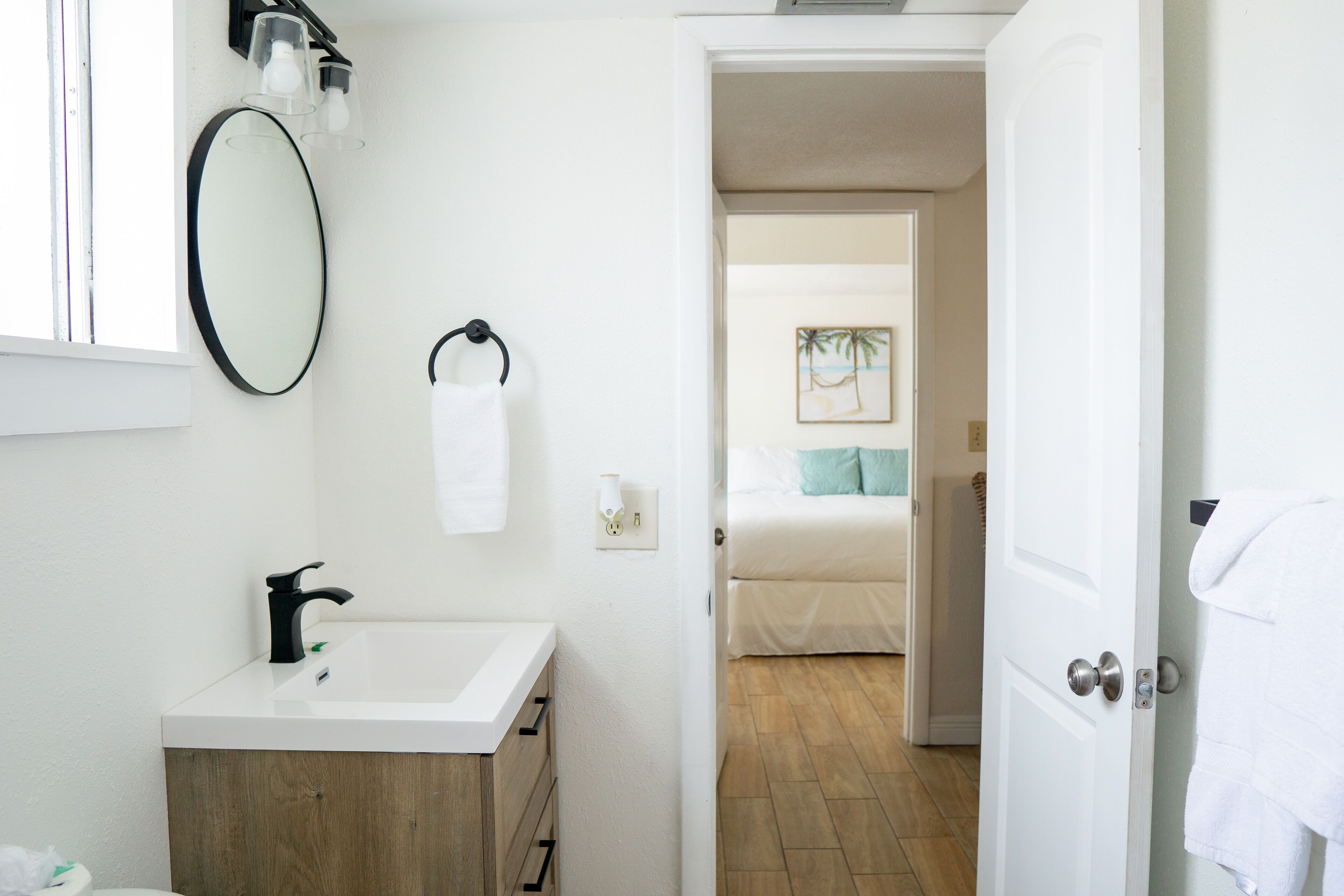 Un baño con un lavabo blanco, un espejo y un perchero para toallas.