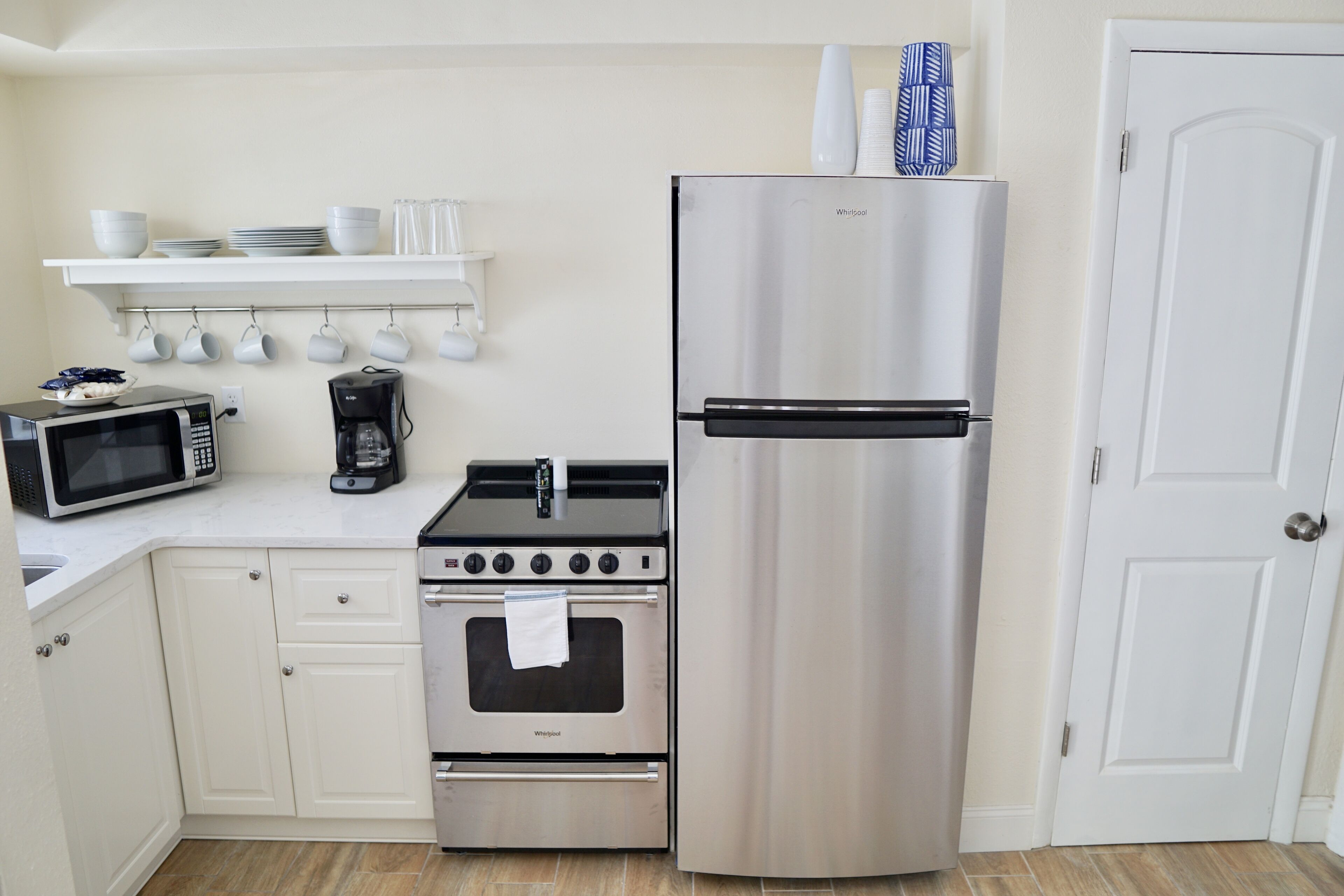 A kitchen with a stainless steel refrigerator, a microwave, a coffee maker, and a stove.
