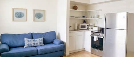 A modern kitchen with white cabinetry, a stainless steel refrigerator, and a built-in oven.