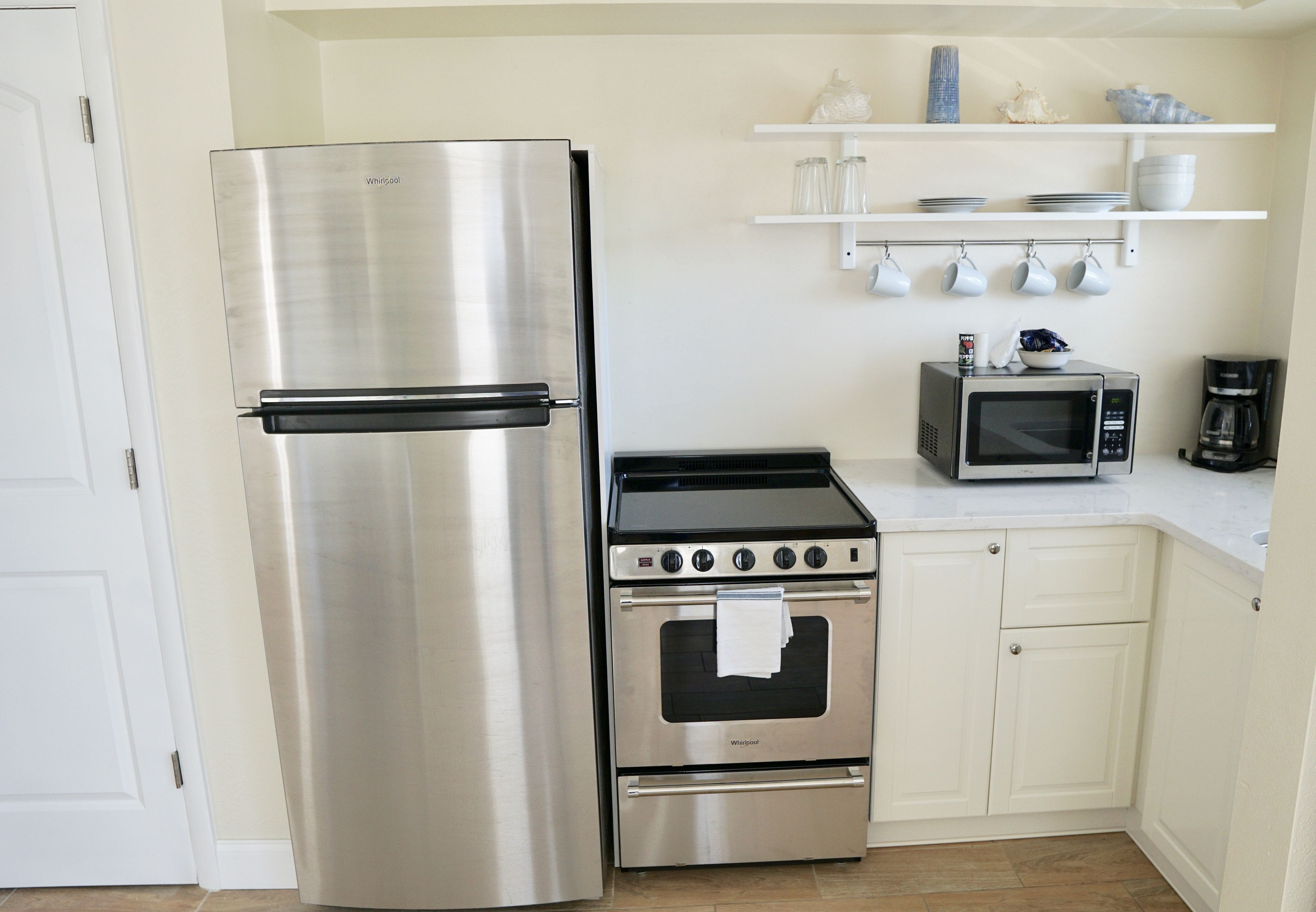 Una cocina con refrigerador de acero inoxidable, horno empotrado, microondas y cafetera.