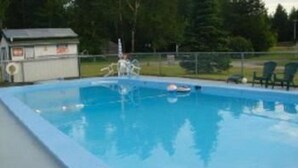 A rectangular swimming pool with a lifeguard tower and a small building in the background. - Patio Motor Court (Twin Mountain)