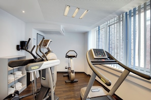A gym with treadmills, an elliptical, and a stationary bike, with large windows and a high ceiling. - Holiday Inn Express Bremen Airport by IHG (Bremen)