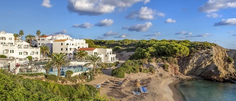 A coastal town with white buildings, a beach, and a clear blue sky.