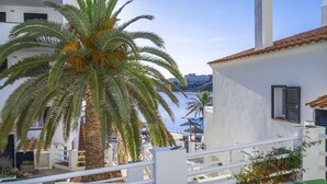 A coastal building with white walls and a tiled roof, overlooking a calm sea. - White Sands Beach Club (Mercadal)