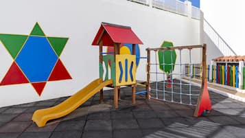 Explore the vibrant play area with a slide, climbing structure, and netted climbing frame.