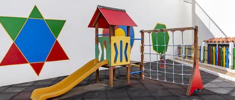 A children's play area with a slide, climbing structures, and a colorful wall design.