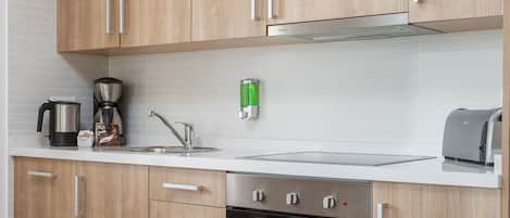 Una cocina moderna con armarios de madera, horno integrado, cafetera y tostadora.